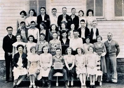 High-school students in rows in front of their school, girls seated in front and boys standing behind.