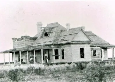 A frame ranch house with wide porches and outbuildings on open prairie.