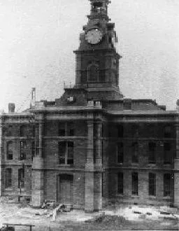An early photograph of the Clay County Courthouse: a tall brick building with a clock tower rising from the center of its roof.