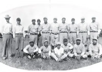 A baseball team in uniform, one row standing and one kneeling.