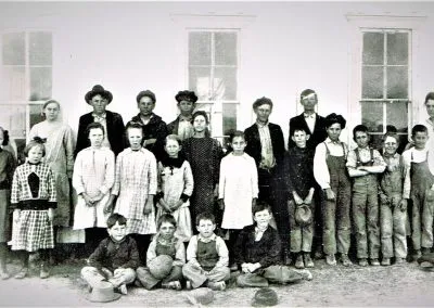 Children of many ages posed outdoors in rows for a school photograph.