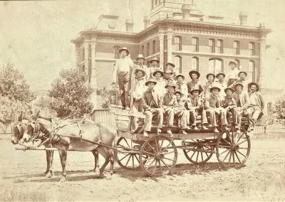 The threshing crew seated on horse-drawn wagons, teams hitched and waiting.