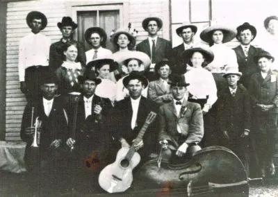 Musicians holding guitars and other instruments posed with their families.