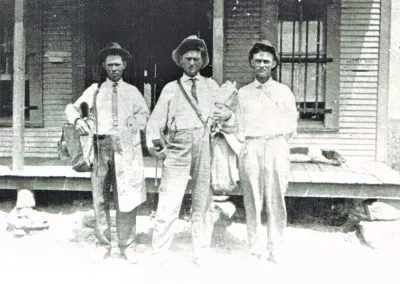 Mail carriers posed in a row in front of a building.