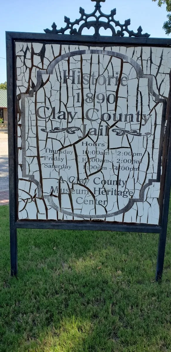 The old museum sign in its iron frame, its painted panel cracked, peeling, and faded almost to illegibility.