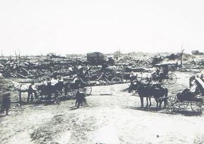 People stand among the splintered wreckage of buildings after a tornado.