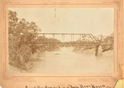 An old mounted photograph of a bridge spanning the Wichita River.